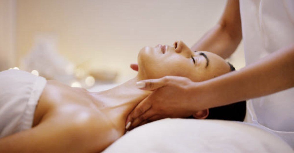 A therapist massaging a relaxed client&rsquo;s neck and shoulders