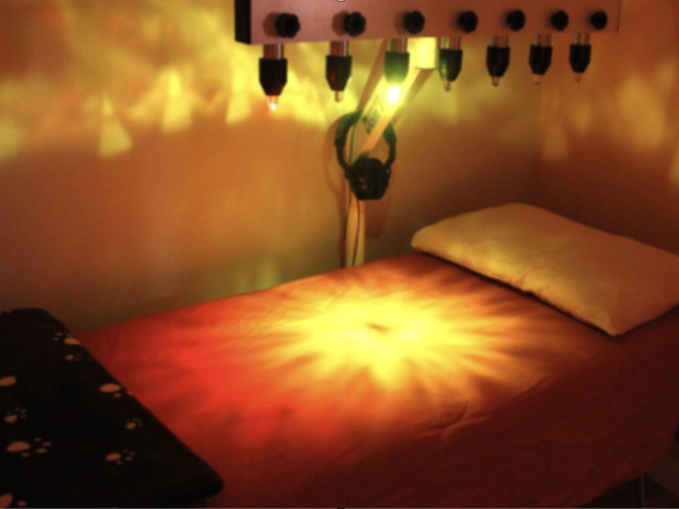 A crystal light bed set up with warm colored light frequencies and headphones for sound