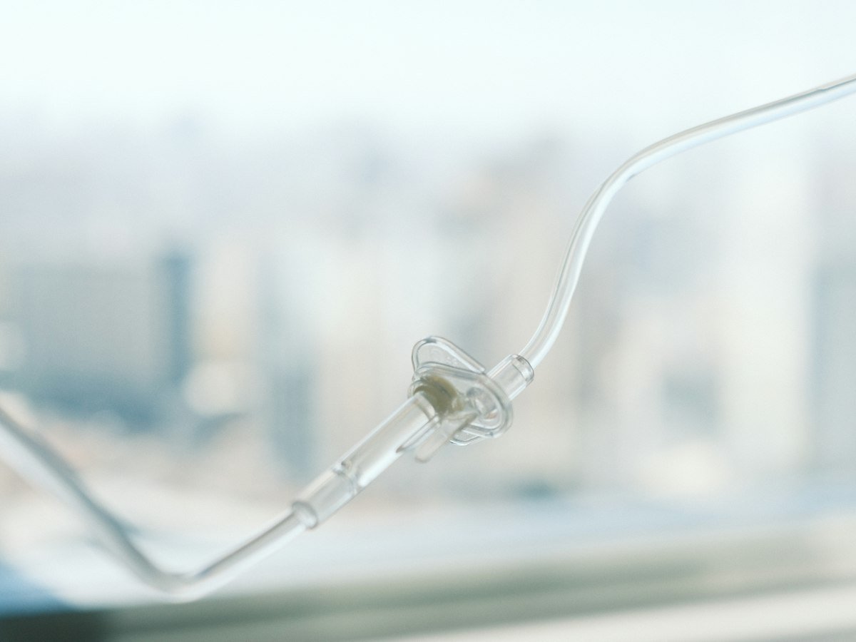 A clear IV line in soft daylight in front of a bright, blurred window