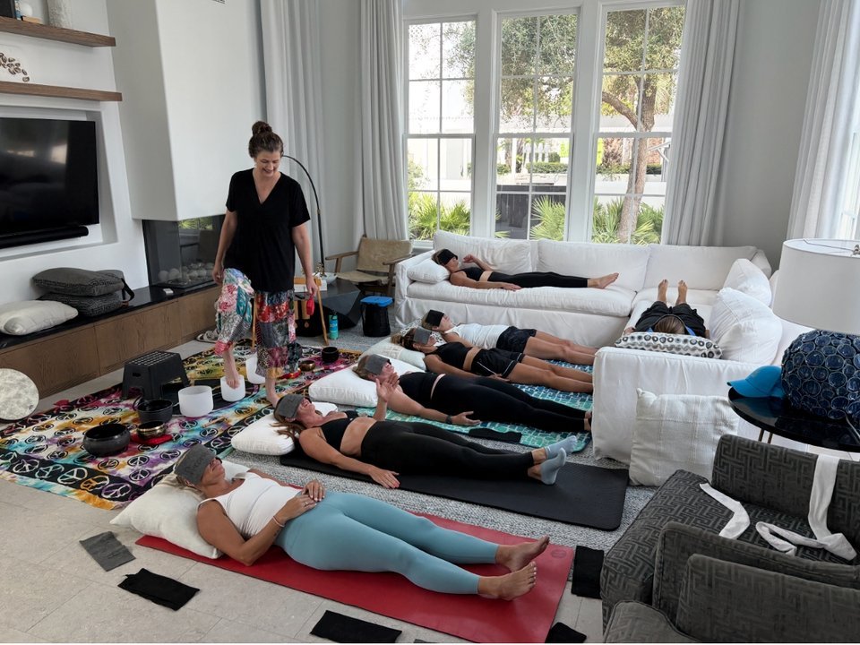Guests relaxing during a guided sound bath and breathwork session, with sound bowls arranged nearby