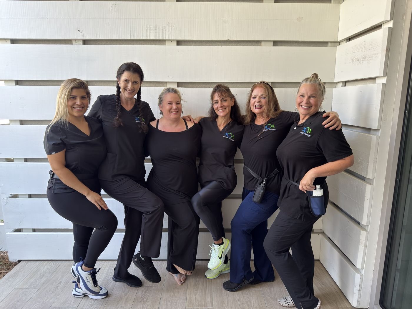 The 30A Mobile Massage team of six therapists smiling together outside